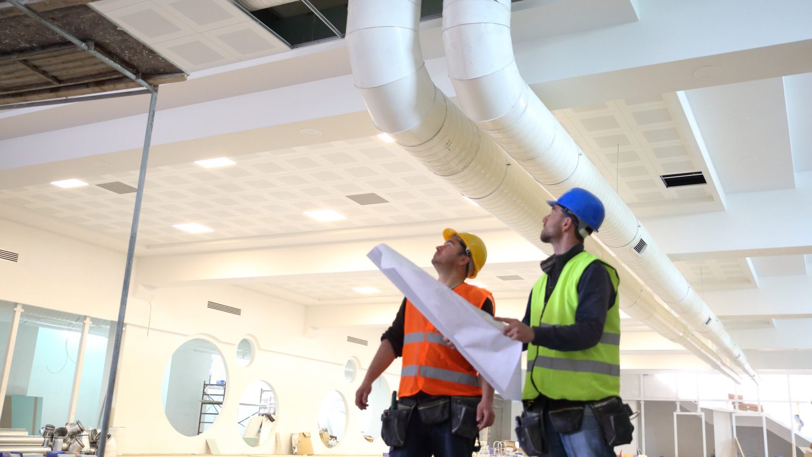 Construction workers looking at blueprints inside construction site.